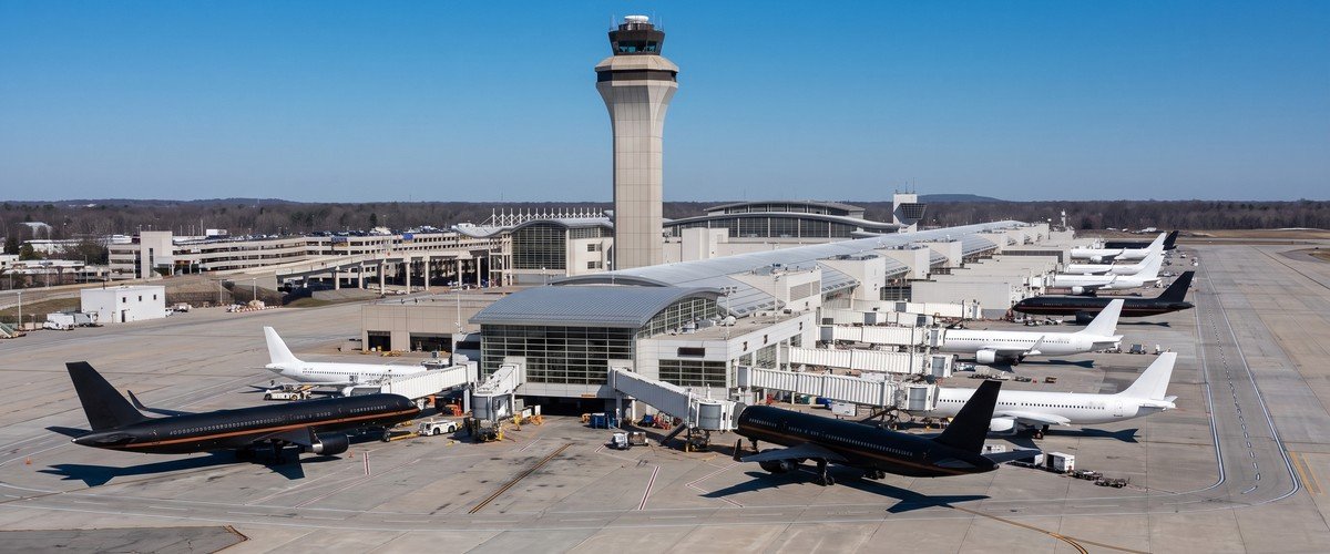 Aircraft parked at a terminal and along a taxiway below a control tower - illustrative context